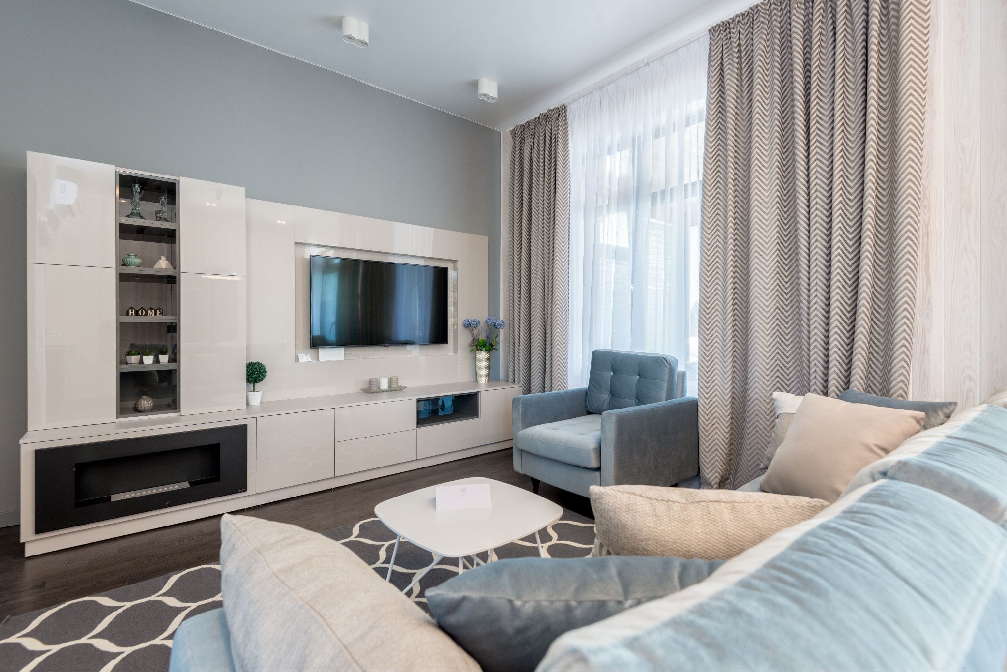 Imperial Beach apartment interior with white cabinets, grey furniture, and a wall-mounted television
