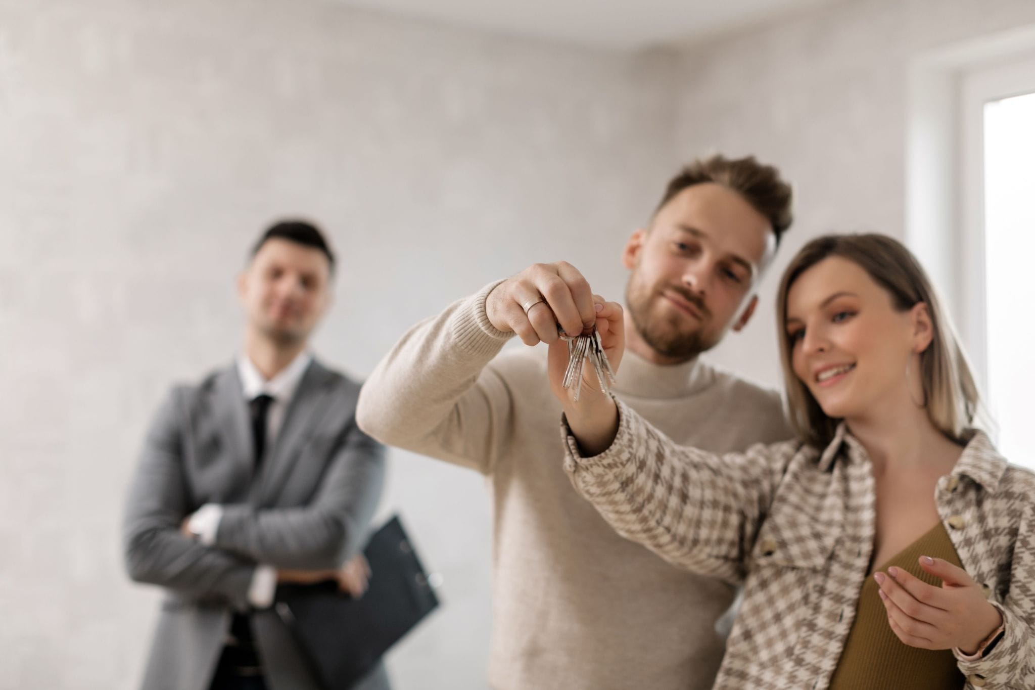 Tenants holding the keys to their new rental while the property manager stands behind them
